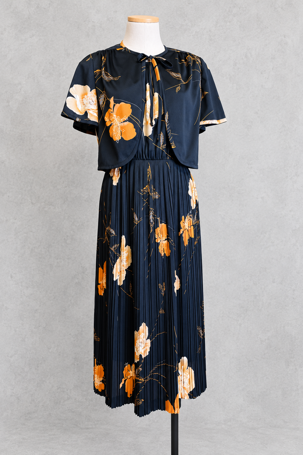 Robe vintage mi-longue avec bolero noire à motifs floraux orange et écru – col rond, jupe plissée