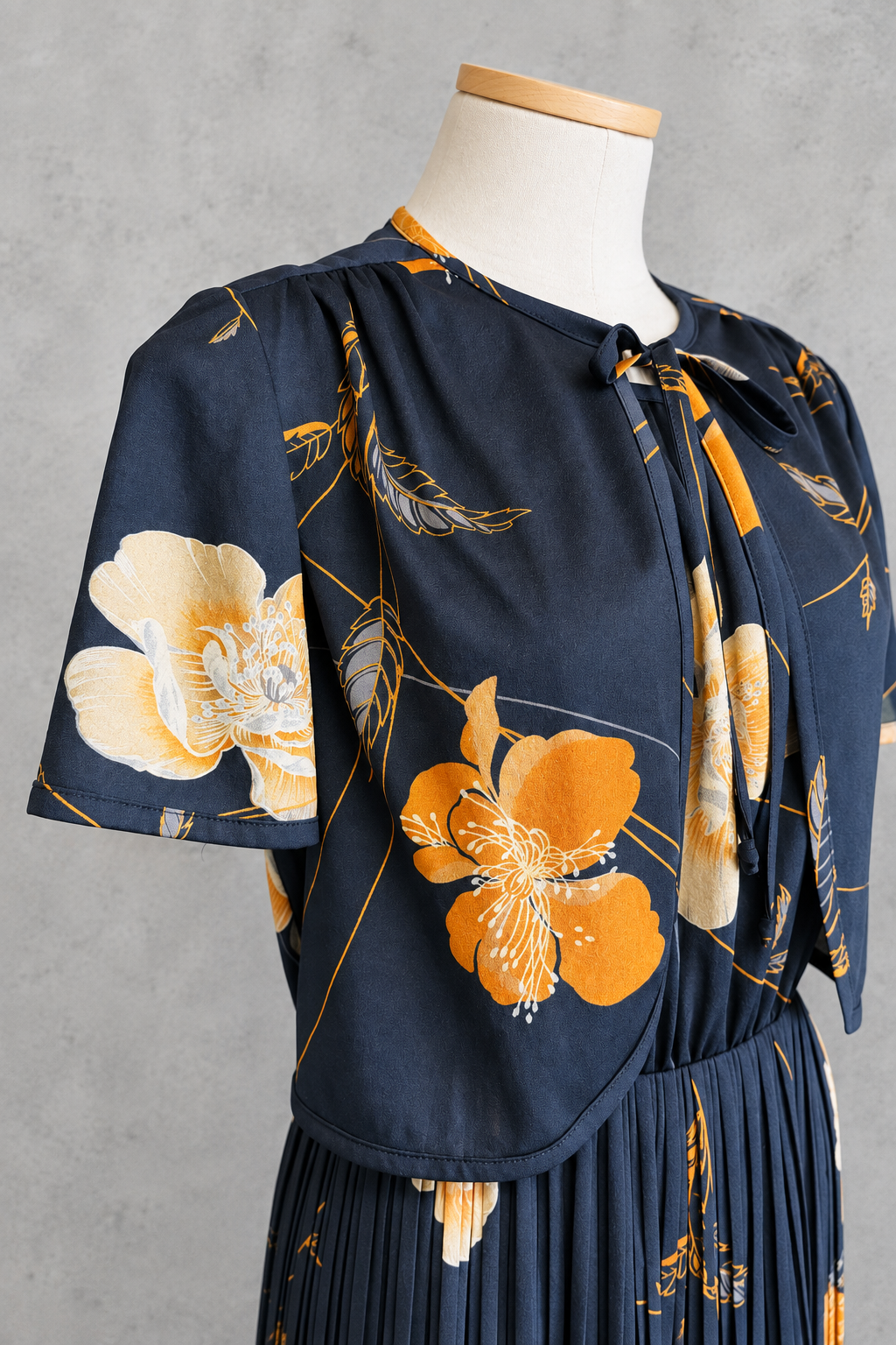 Robe vintage mi-longue avec bolero noire à motifs floraux orange et écru – col rond, jupe plissée