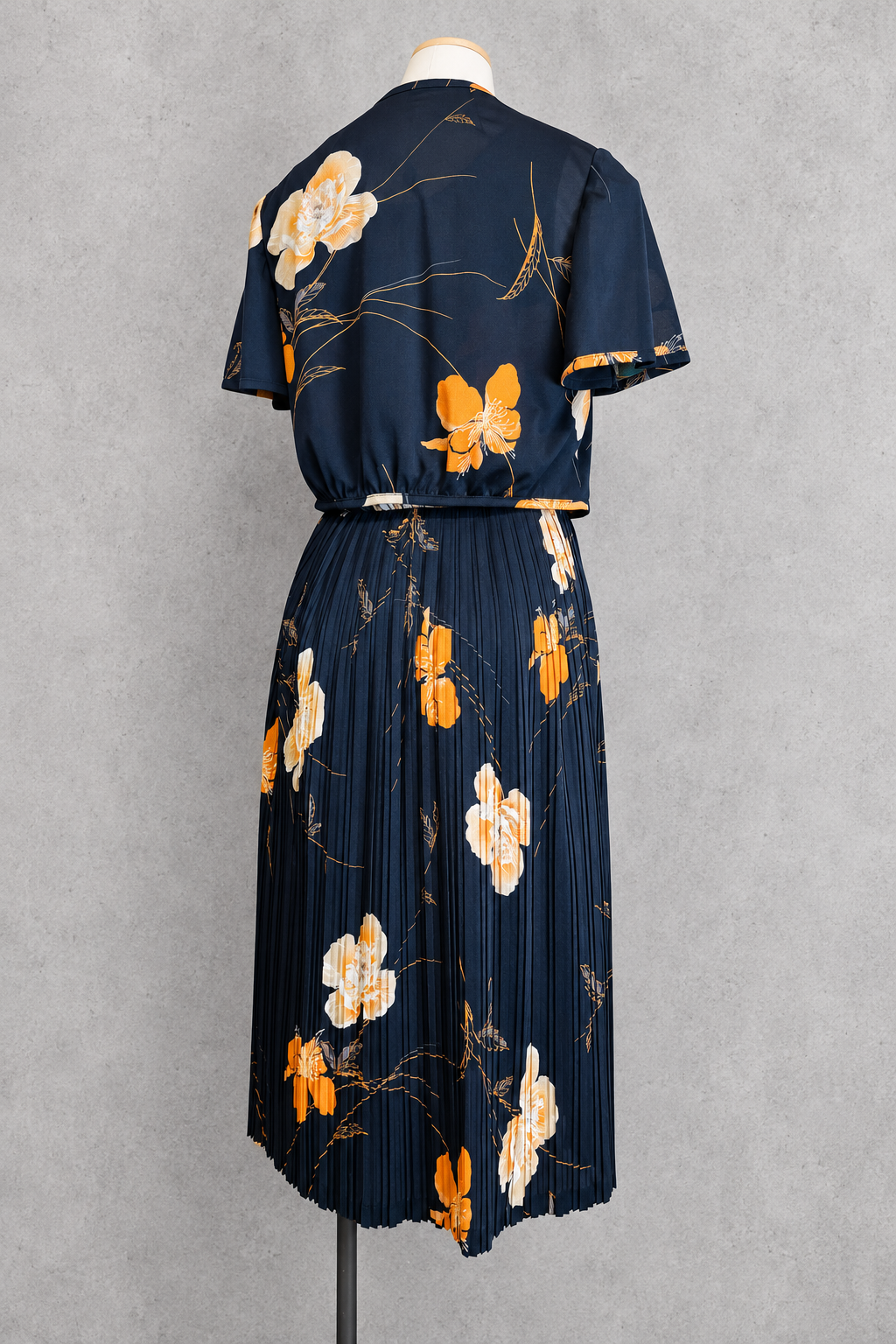 Robe vintage mi-longue avec bolero noire à motifs floraux orange et écru – col rond, jupe plissée